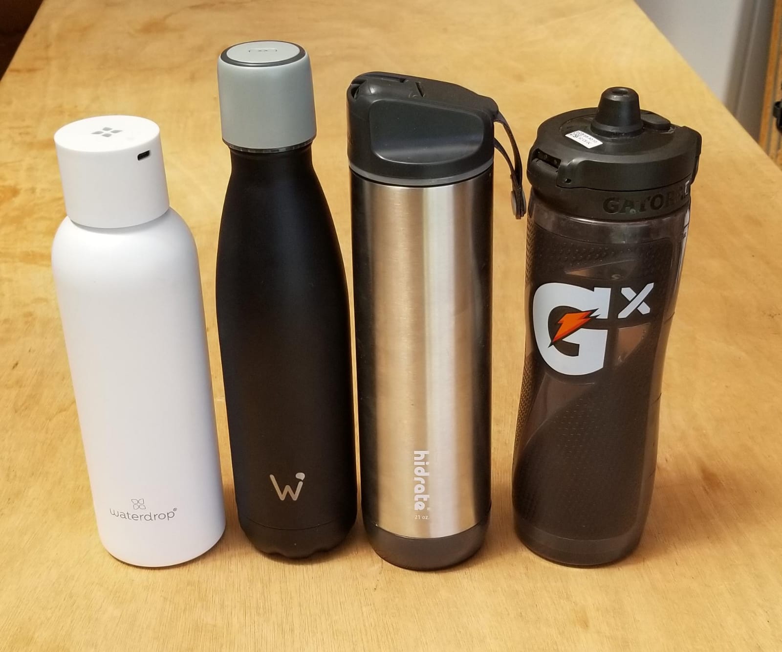 Lineup of four smart water bottles — WaterDrop with LUCY smart cap, water.io, HidrateSpark Pro, and Gatorade Smart Gx