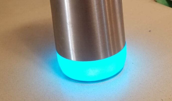 HydrateSpark Pro smart water bottle with base glowing blue after being refilled